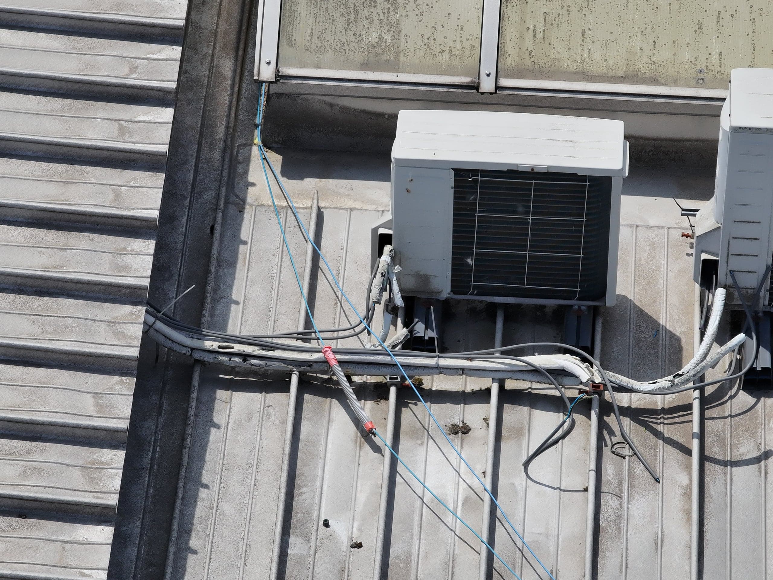 Detail van een HVAC-unit en kabeldoorvoeren op een metalen dak